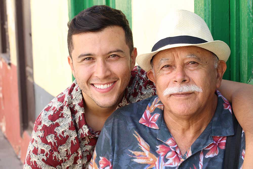 Adult son and senior father smiling together outdoors.